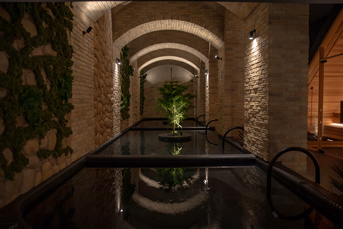Brick arches over the dark-tiled bathing pool at Navia Bathhouse Prahran